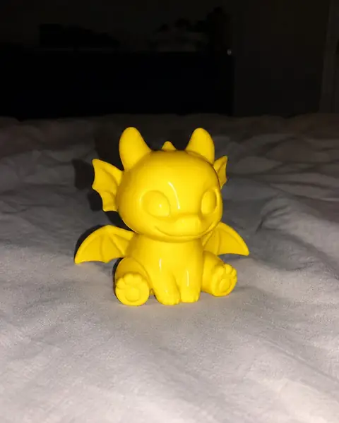 A glossy yellow printed dragon figurine on fabric