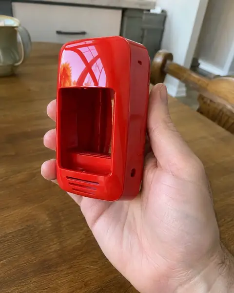 A glossy red printed device housing held in a hand
