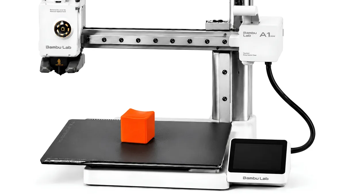 An orange practice cube fresh off a Bambu Lab A1 mini 3D printer