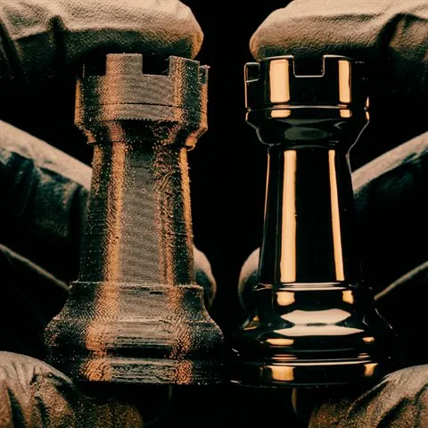 Raw 3D printed rook beside a smooth finished rook